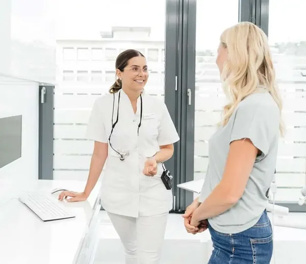 Zahnärztin und Patientin stehen im Behandlungszimmer und sprechen über den Behandlungsplan