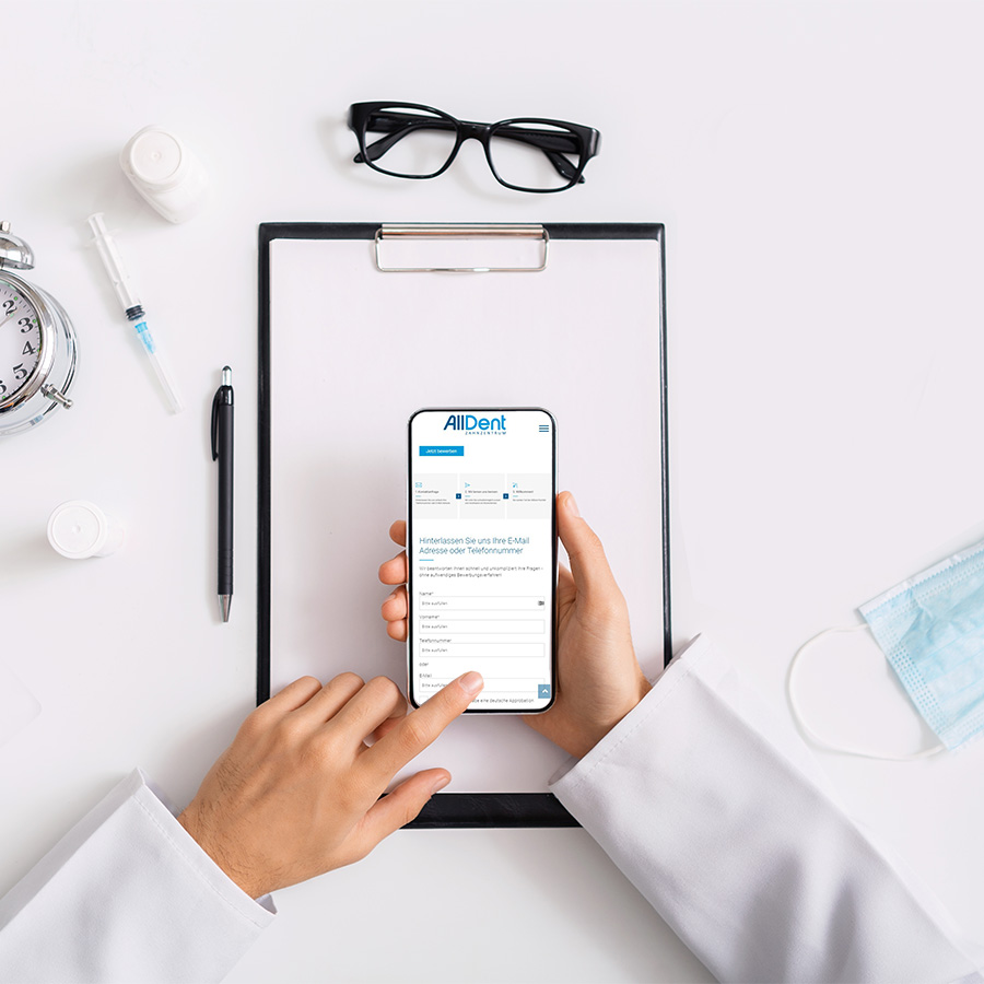 H&auml;nde tippen auf Handydisplay, darunter liegt ein Klemmbrett, eie Brille, ein Kugelschreiber