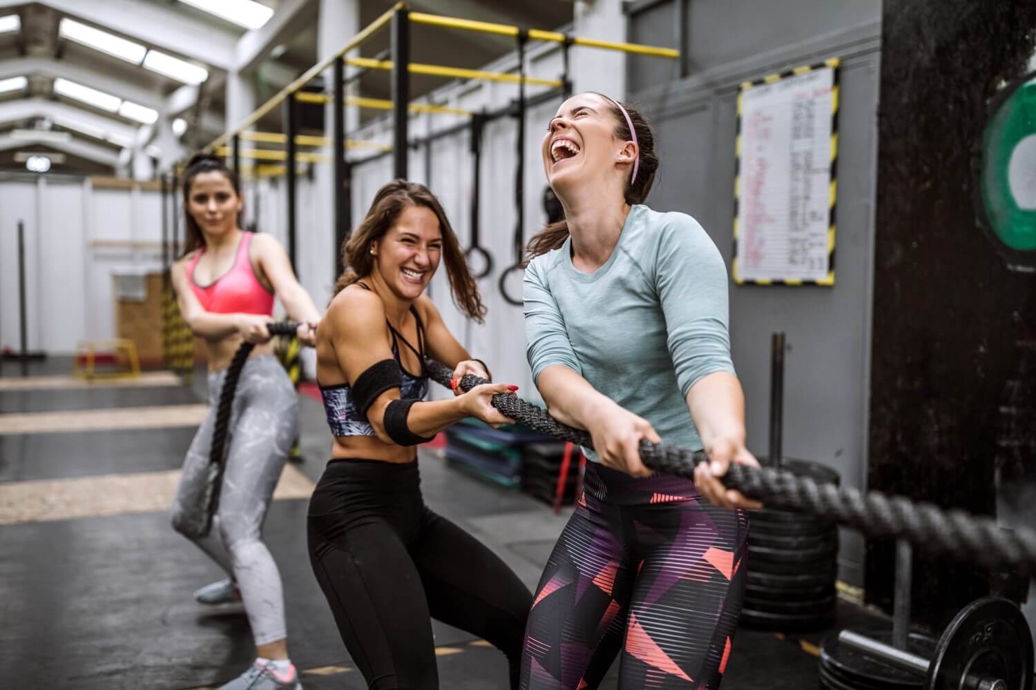 Drei Personen ziehen ein Seil im Fitnessstudio